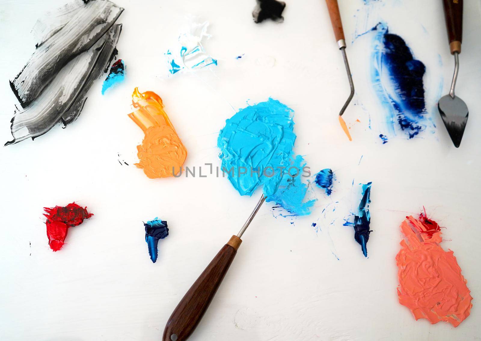 Detail of paint brushes and bright paint in an artist’s studio by fivepointsix