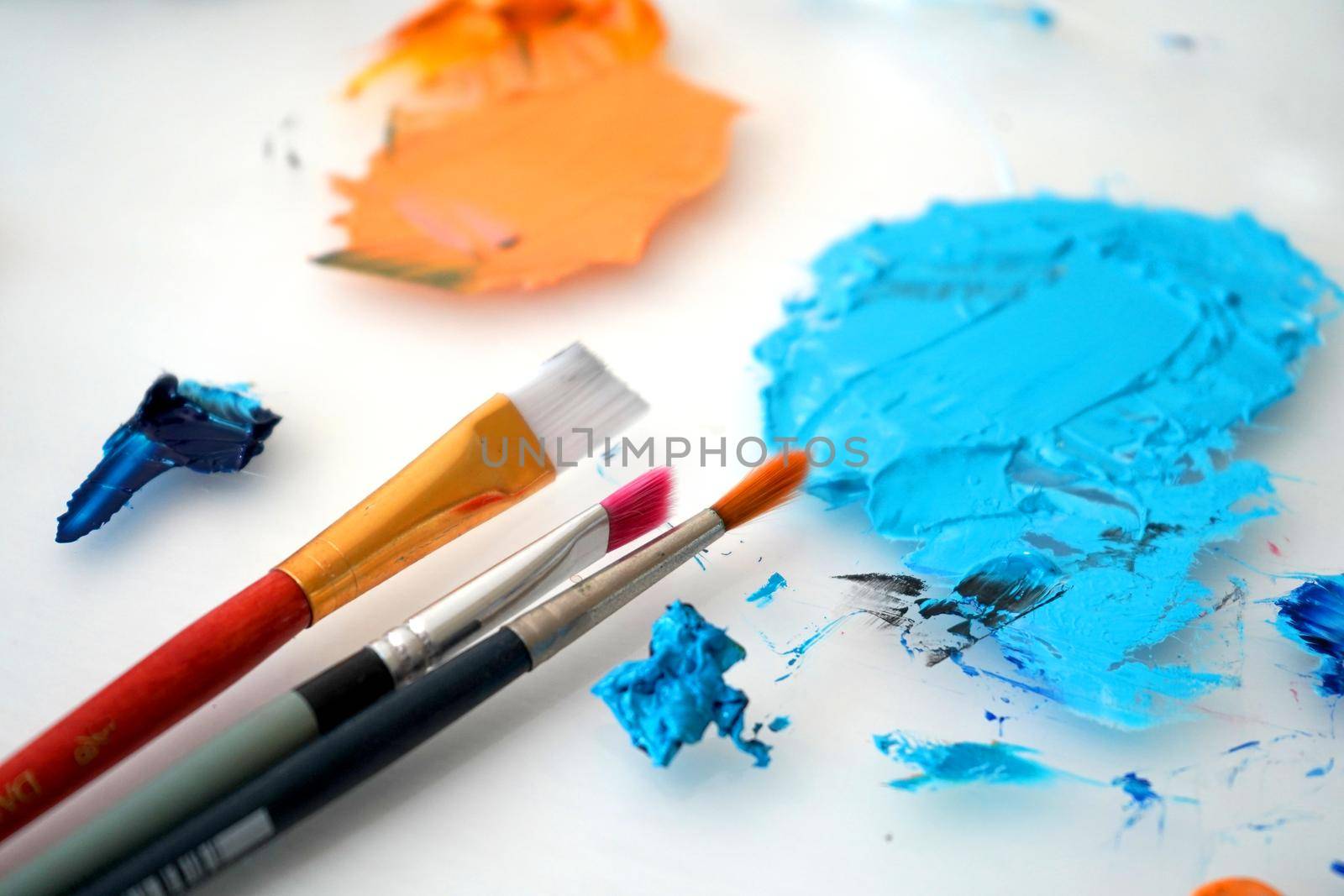 Detail of paint brushes and bright paint in an artist’s studio by fivepointsix