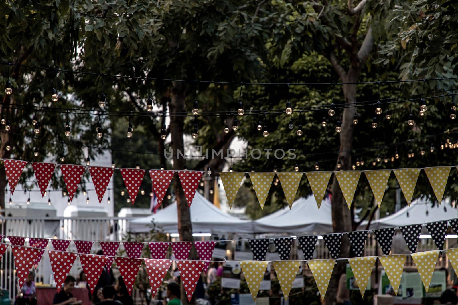 Bangkok, Thailand - 22 Dec 2019 : Triangular flags and lighted bulb of decorated for celebrated in garden of evening.