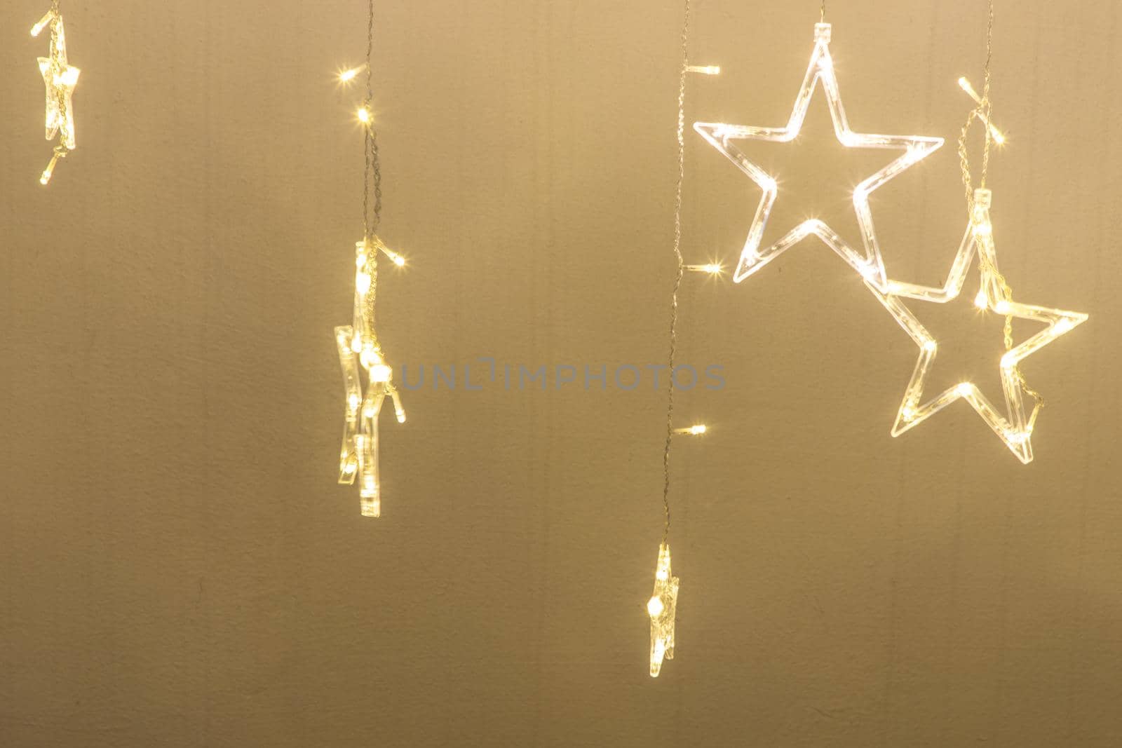 Christmas golden lights in the shape of a star on a background of wall,  Yellow shiny illumination, Christmas decor, copy space, Selective focus.
