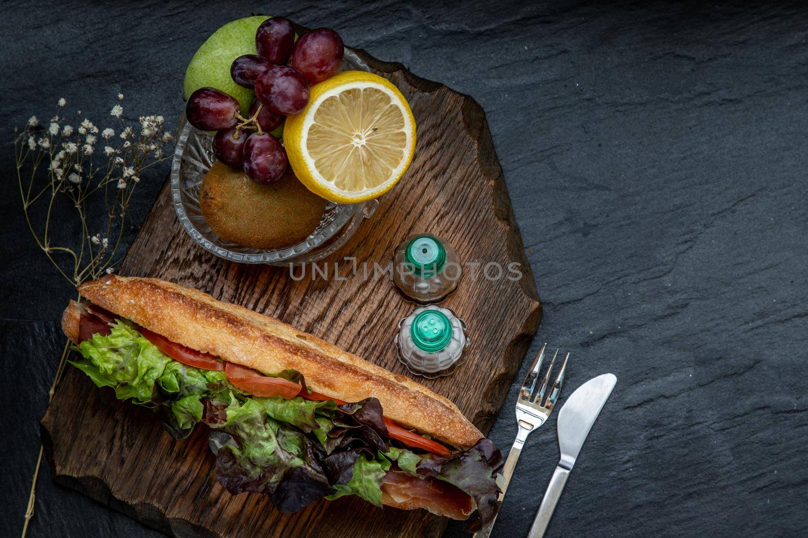 A delicious Smoked salmon sesame bread sandwich with Fresh fruit on a wooden plate. It is perfect eaten with salads and flavoursome cheeses. Healthy breakfast food. Top view. Place for text.
