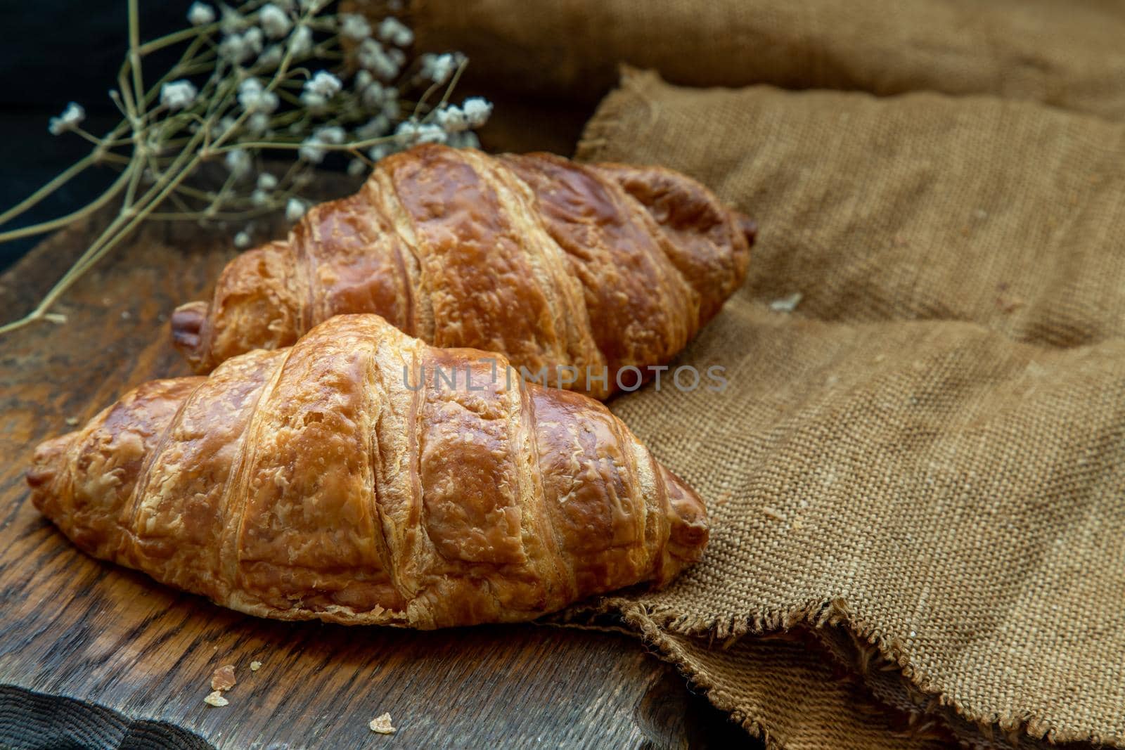 Delicious fresh croissants placed on a wooden plate ready to eat. A delicious French breakfast. Oblique view from the top. Place for text.