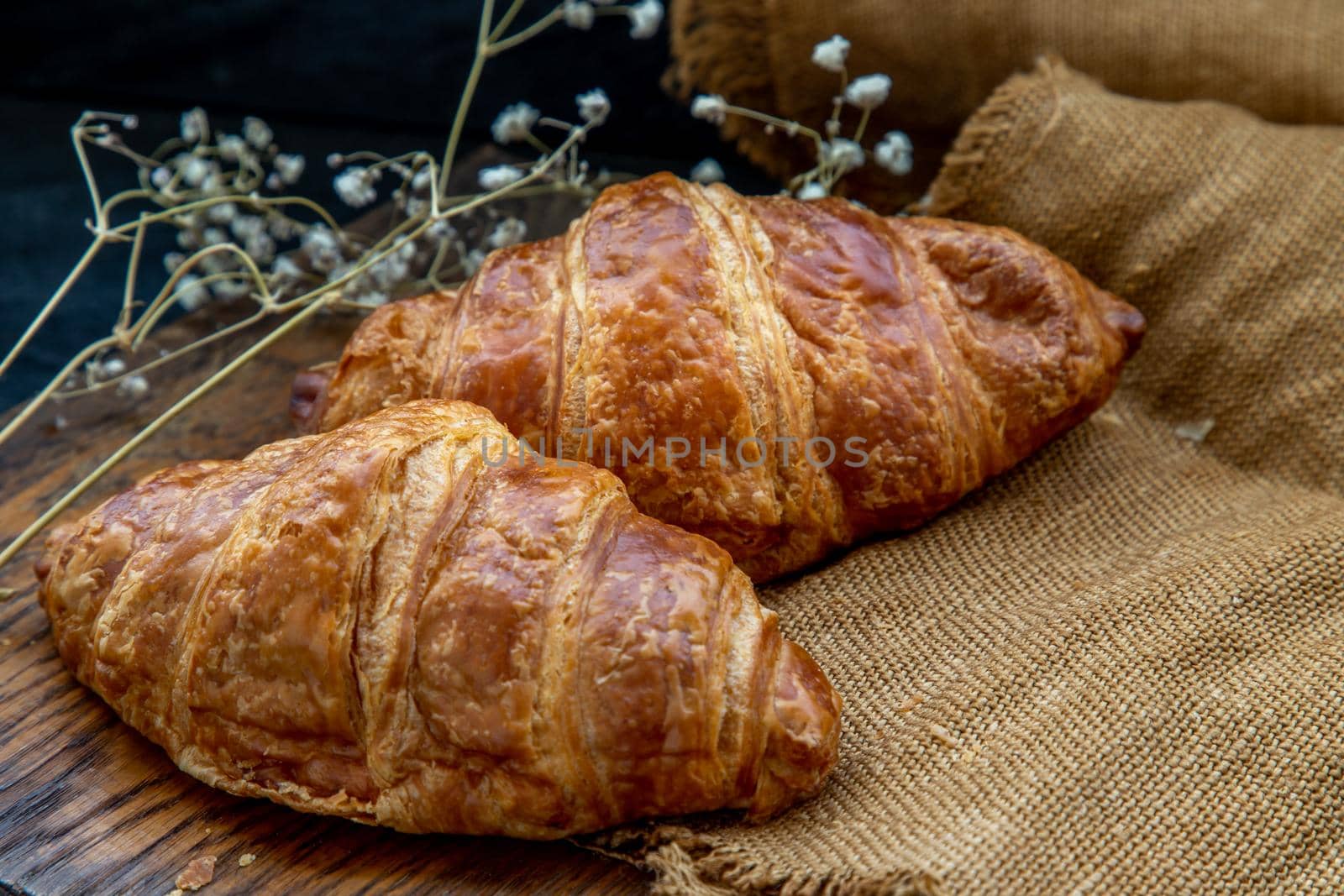 Delicious fresh croissants placed on a wooden plate ready to eat. A delicious French breakfast. Oblique view from the top. Place for text.