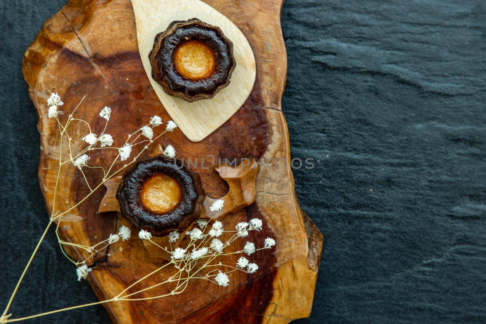 Cannelés (Canelés) de Bordeaux Recipe is a small pastry with rum and vanilla on a wooden plate. Traditional French sweet dessert. tasty snacks. Top view. Place for text.