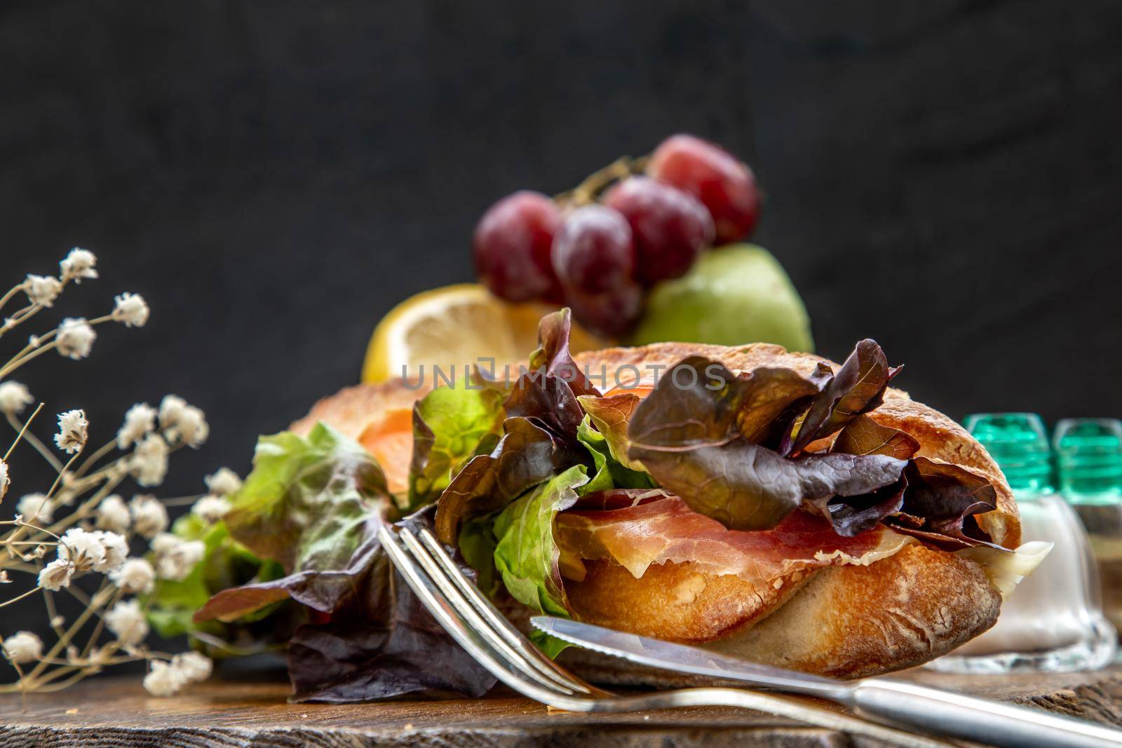 A delicious Smoked salmon sesame bread sandwich on a wooden plate. It is perfect eaten with salads and flavoursome cheeses. Healthy breakfast food.