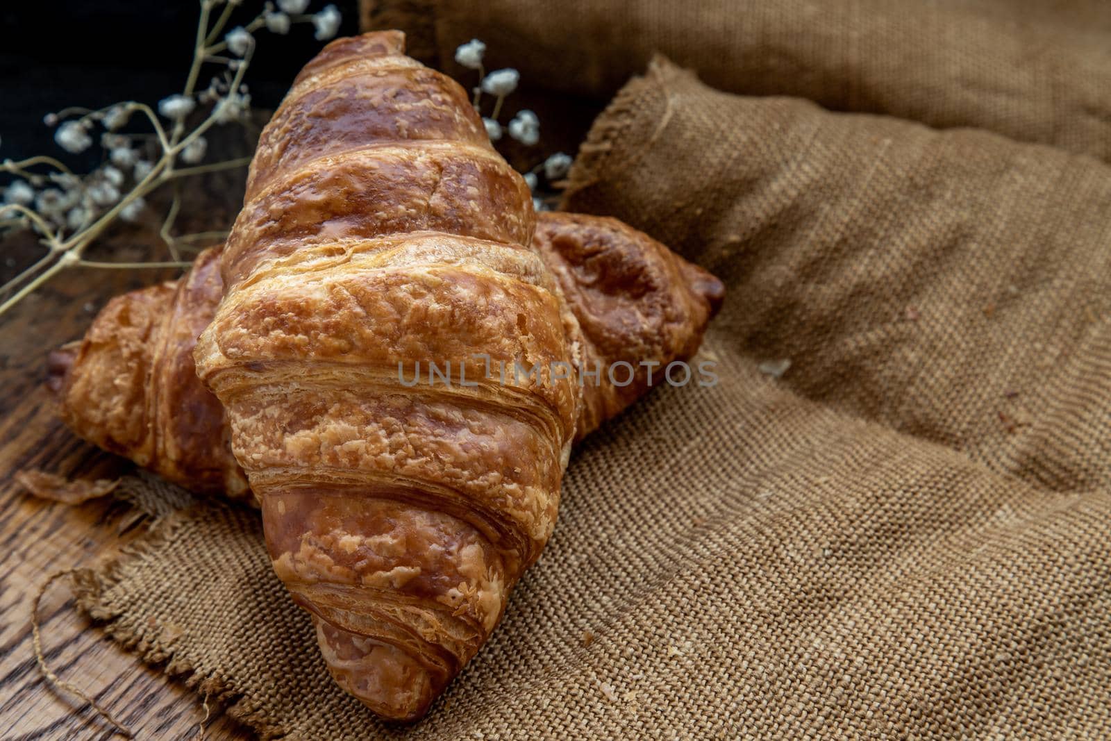 Delicious fresh croissants placed on a wooden plate ready to eat. A delicious French breakfast. Oblique view from the top. Place for text.