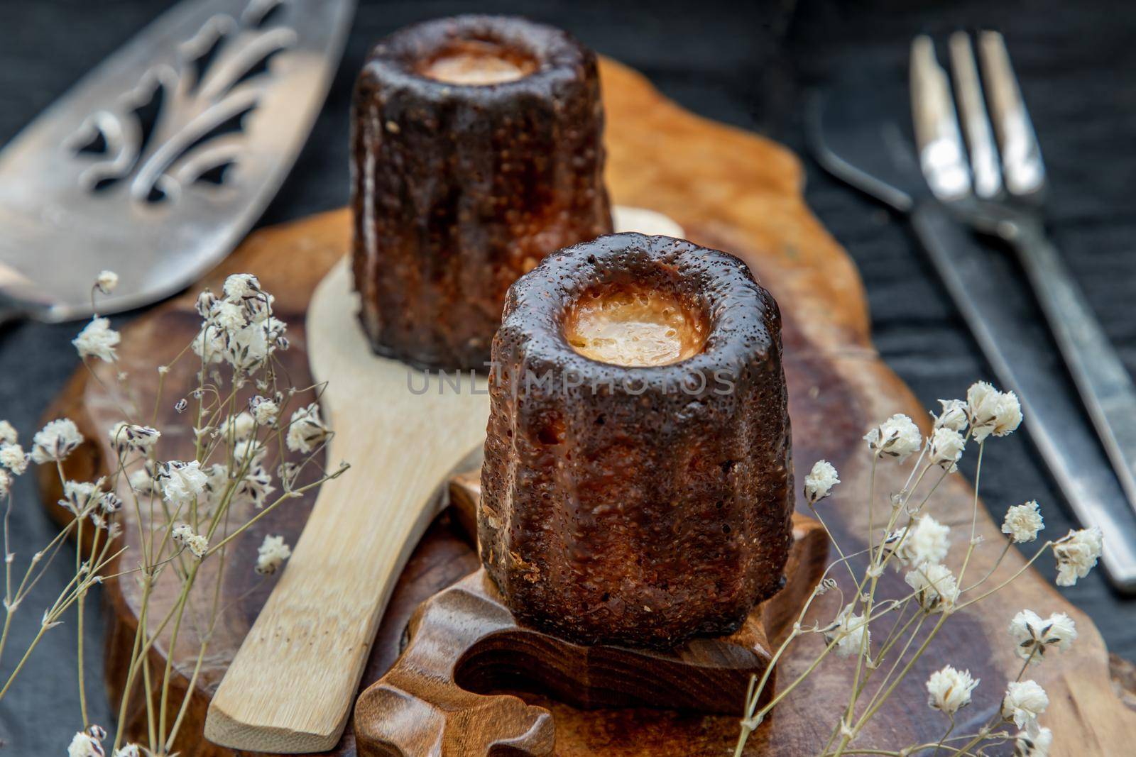 Cannelés (Canelés) de Bordeaux Recipe is a small pastry with rum and vanilla on a wooden plate. Traditional French sweet dessert. tasty snacks. Oblique view from the top.