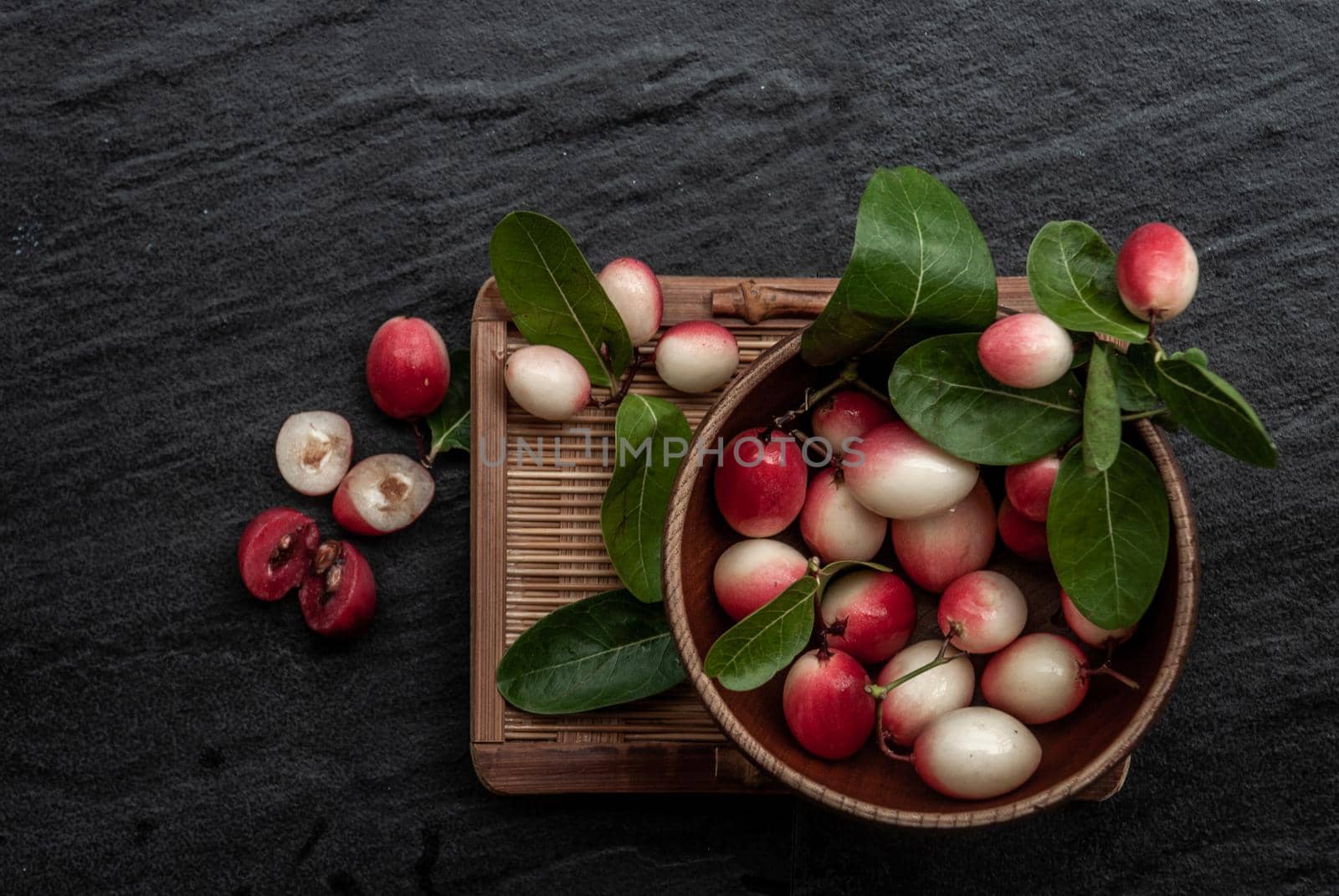 Bengal-Currants, Carandas-plum or Karonda fruit (Carissa carandas L.) sour taste fruit in Wooden cup on wicker. Top view.