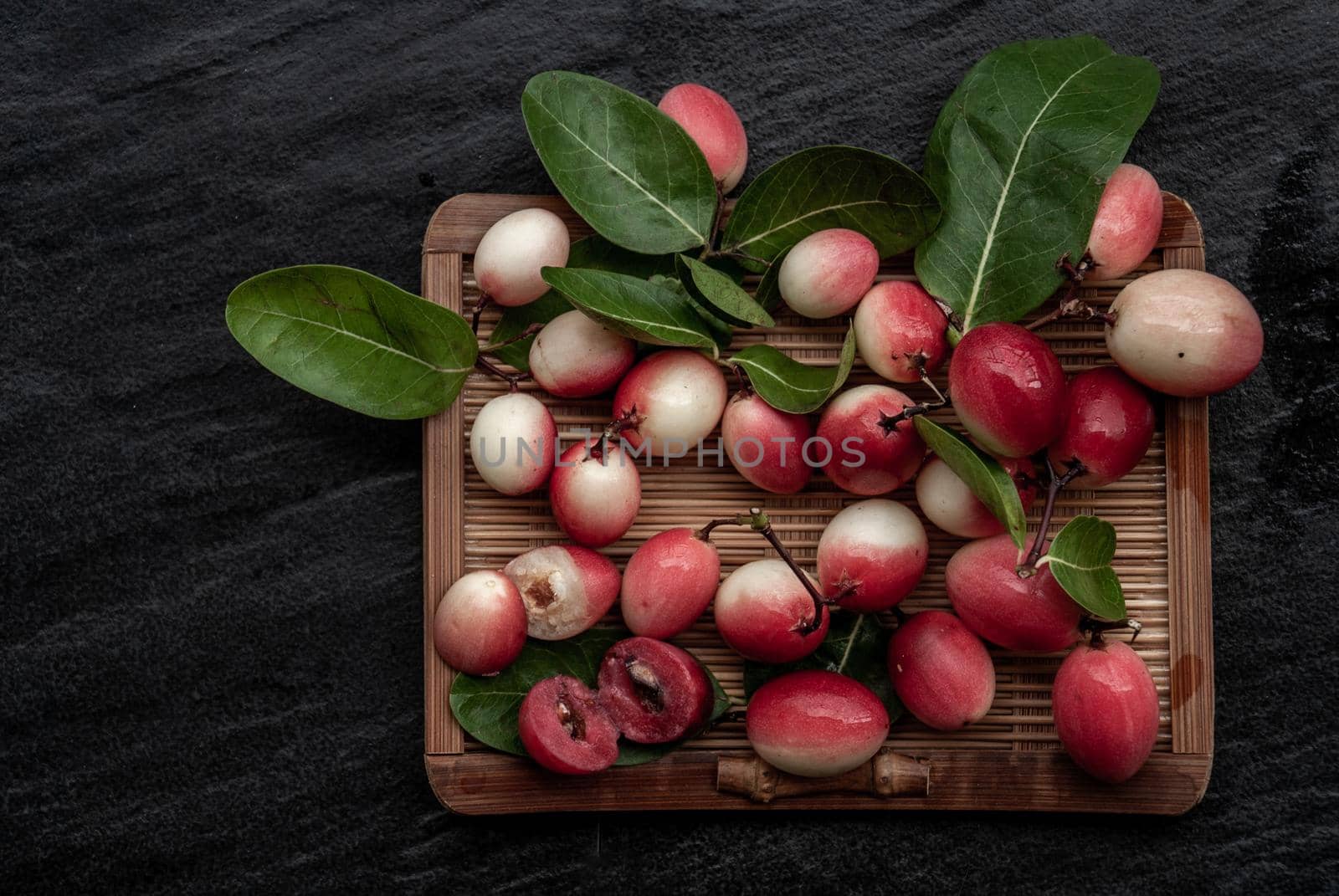 Bengal-Currants, Carandas-plum or Karonda fruit (Carissa carandas L.) sour taste fruit on wicker. Top view.