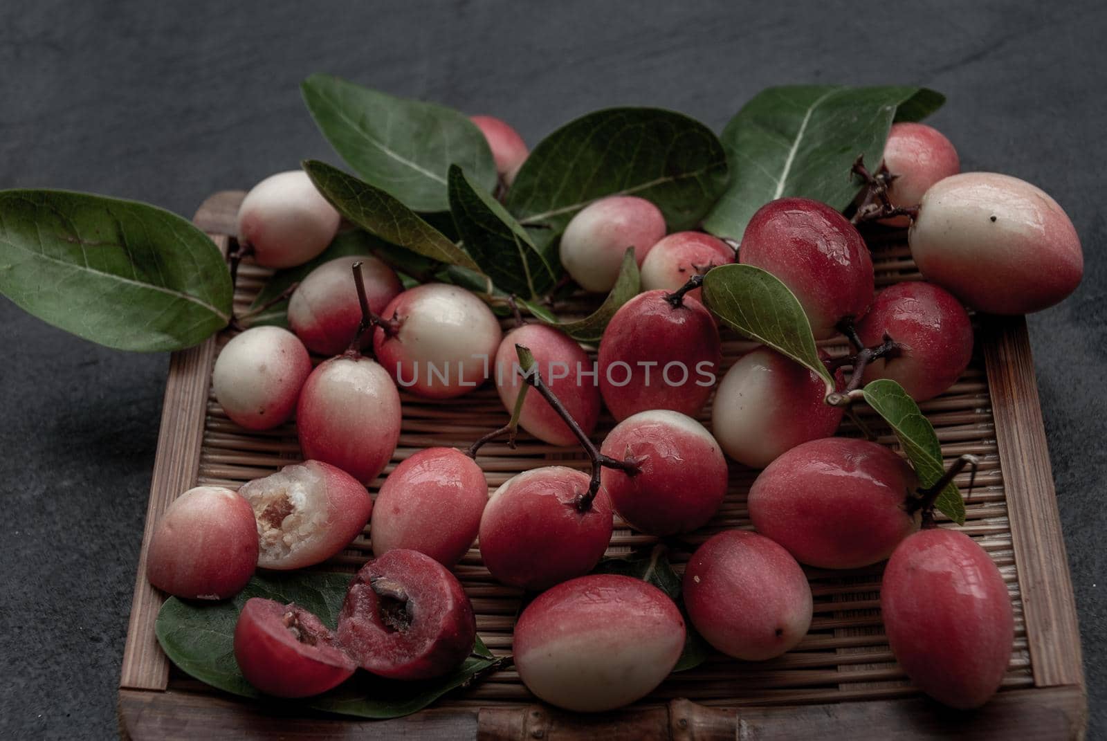 Bengal-Currants, Carandas-plum or Karonda fruit (Carissa carandas L.) sour taste fruit on wicker. Oblique view from the top.