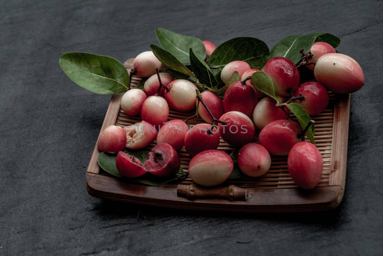 Bengal-Currants, Carandas-plum or Karonda fruit (Carissa carandas L.) sour taste fruit on wicker. Oblique view from the top.