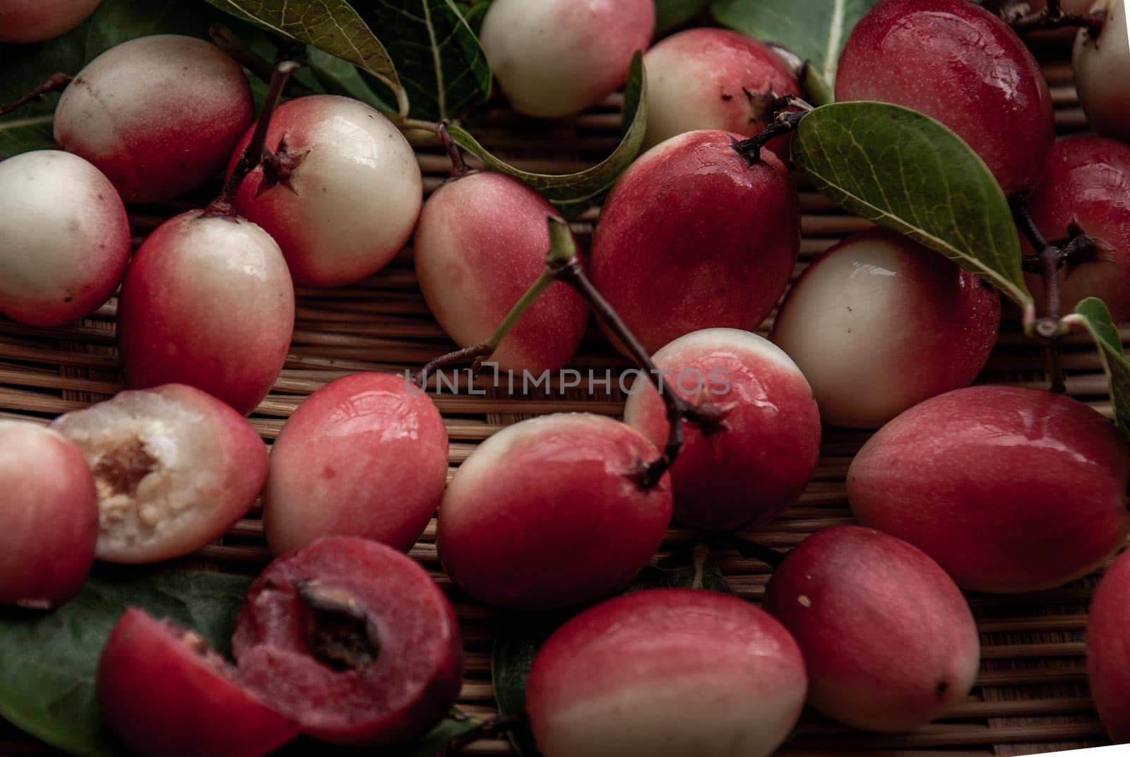 Bengal-Currants, Carandas-plum or Karonda fruit (Carissa carandas L.) sour taste fruit in Wooden cup on wicker. Close-up.