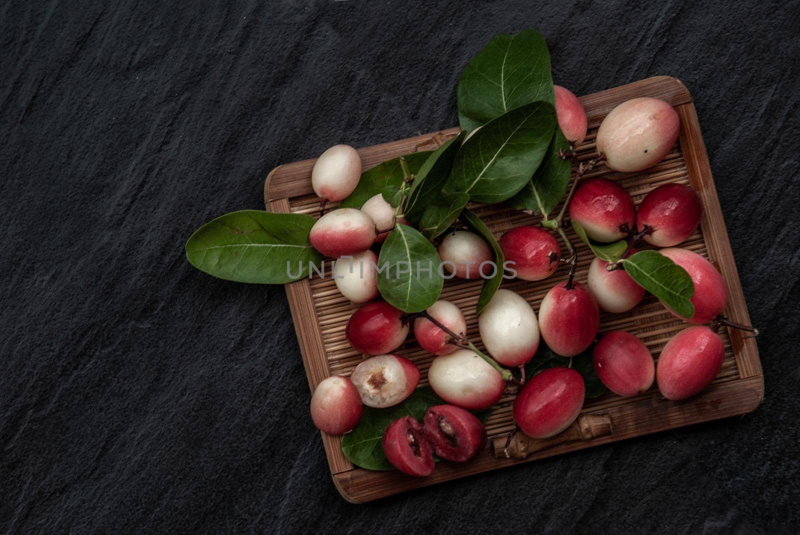 Bengal-Currants, Carandas-plum or Karonda fruit (Carissa carandas L.) sour taste fruit on wicker. Top view.