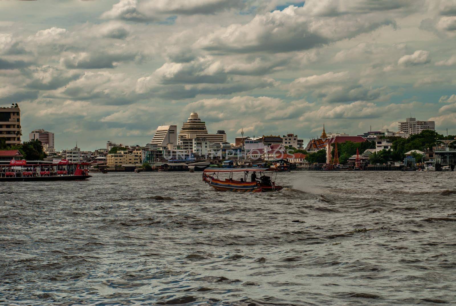 Bangkok, Thailand - 21 Jul 2019 : The passenger ferryboat on the Chao Phraya River showing the several other tall buildings in the background.