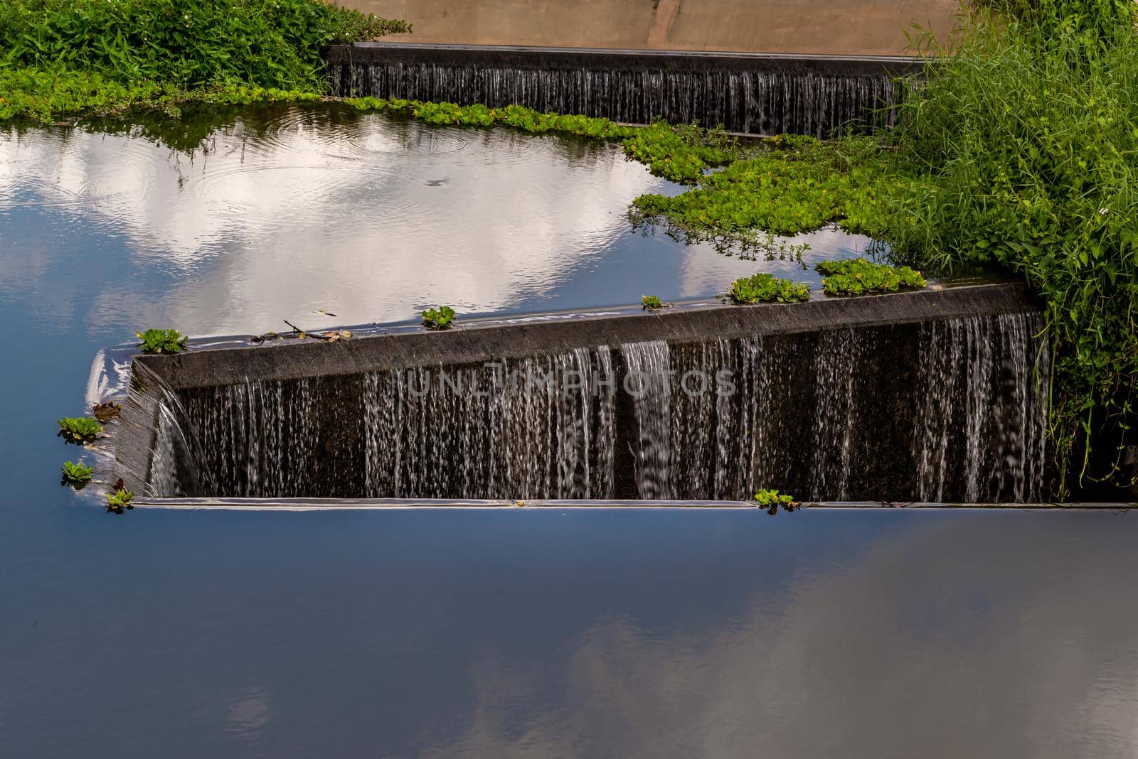 Turbid water in the check dam overflows into the spillway, Man-made Water falling in Tambon Khok Khwai, Amphoe Ban Rai at Uthai Thani, Background of check dam.
