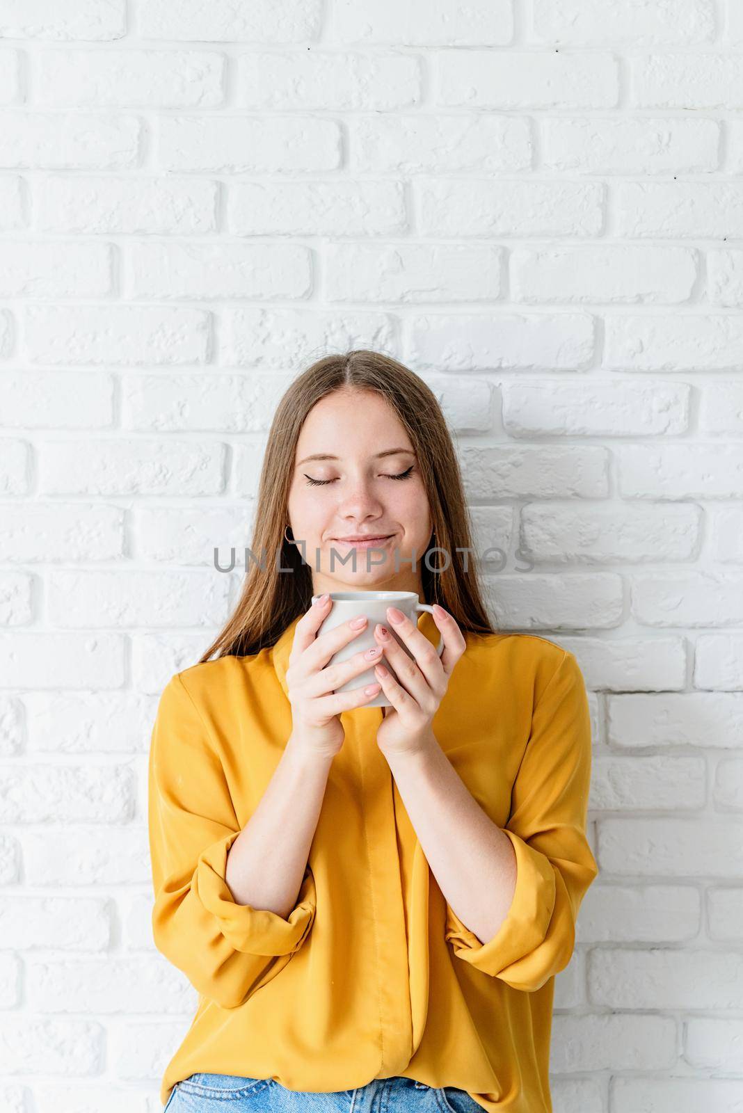 Attractive teenager woman in yellow shirt drinking tea by Desperada