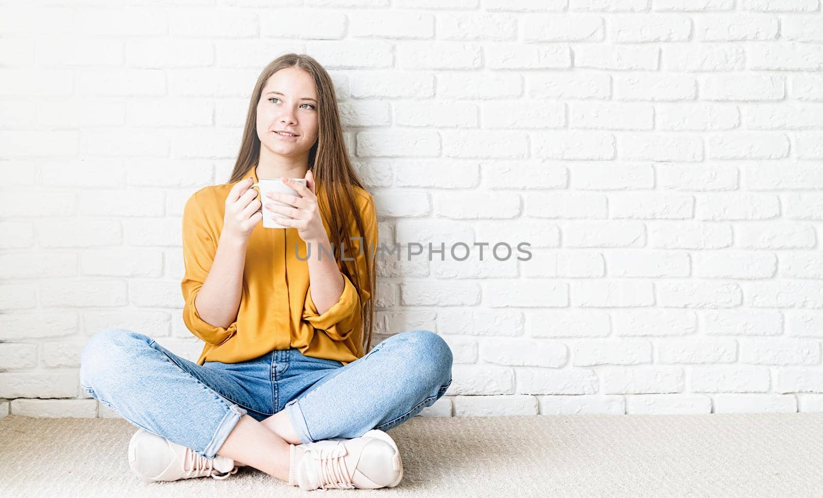 Young attractive woman drinking tea sitting on the floor