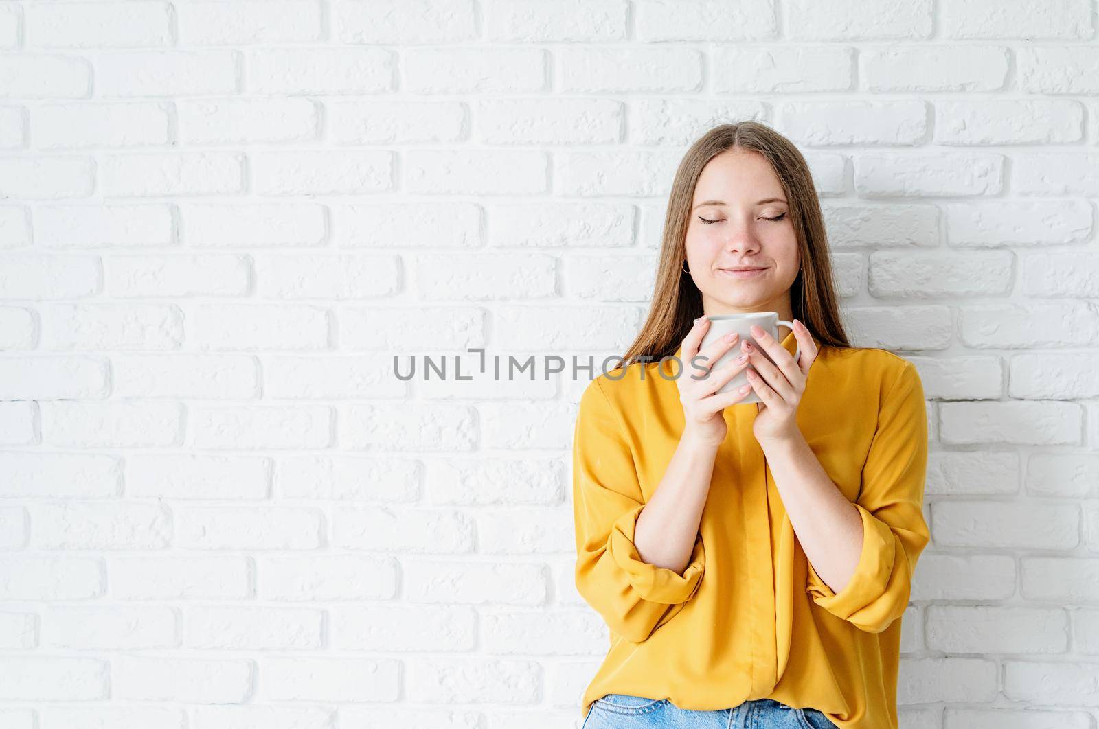 Attractive teenager woman in yellow shirt drinking tea