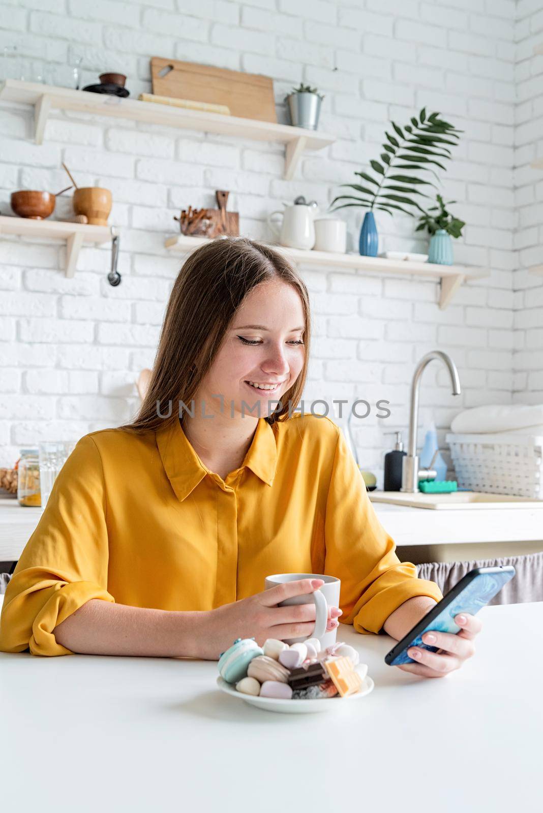 Attractive teenager woman in yellow shirt drinking tea