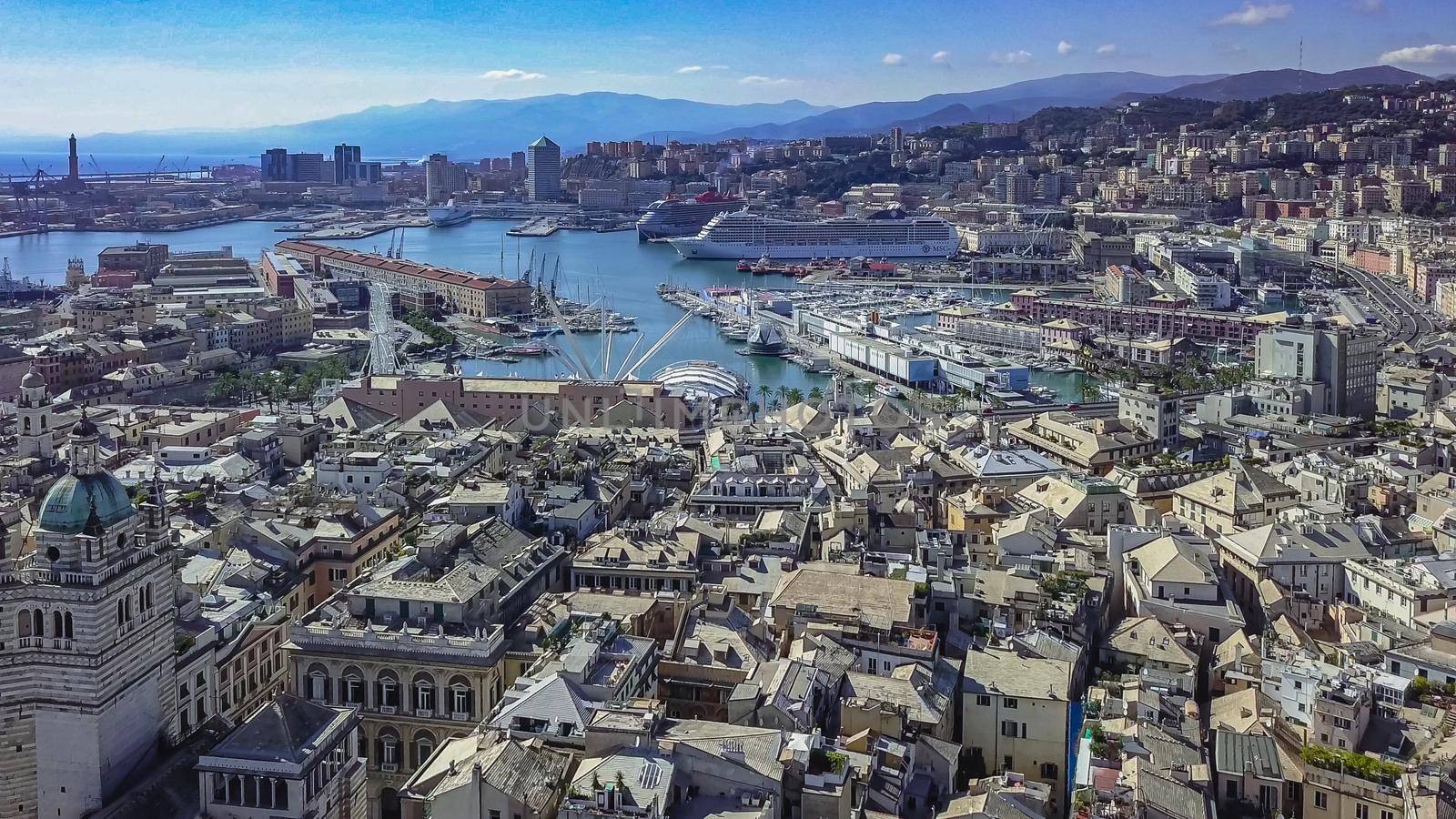 Aerial panoramic drone view of buildings and streets surrounding Port of Genoa.Cruise ship in port. by Angelsmoon