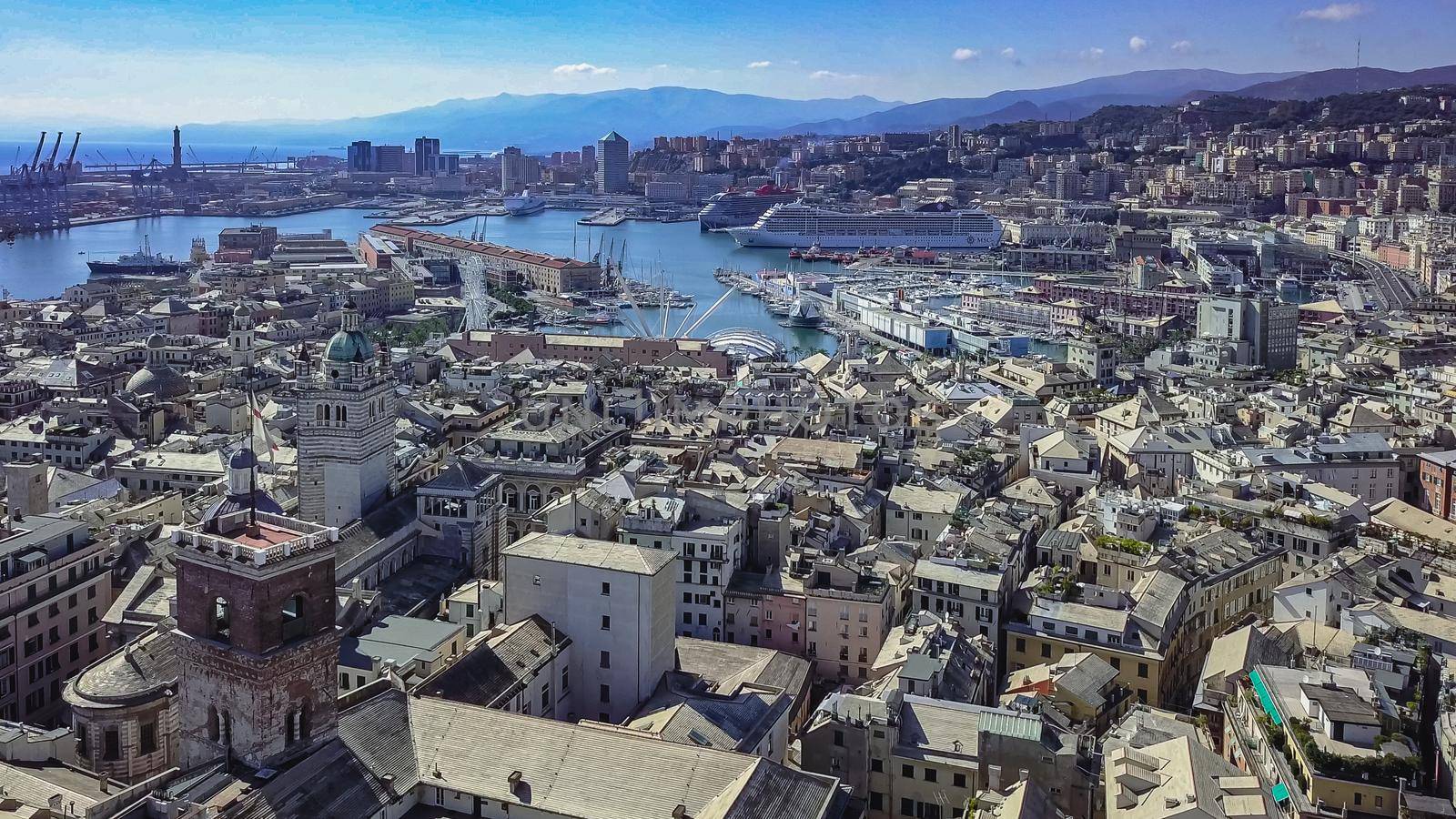 Aerial panoramic drone view of buildings and streets surrounding Port of Genoa.Cruise ships and ferries in port.Old famous city of Italy, with beautiful architecture, houses, roofs, buildings.