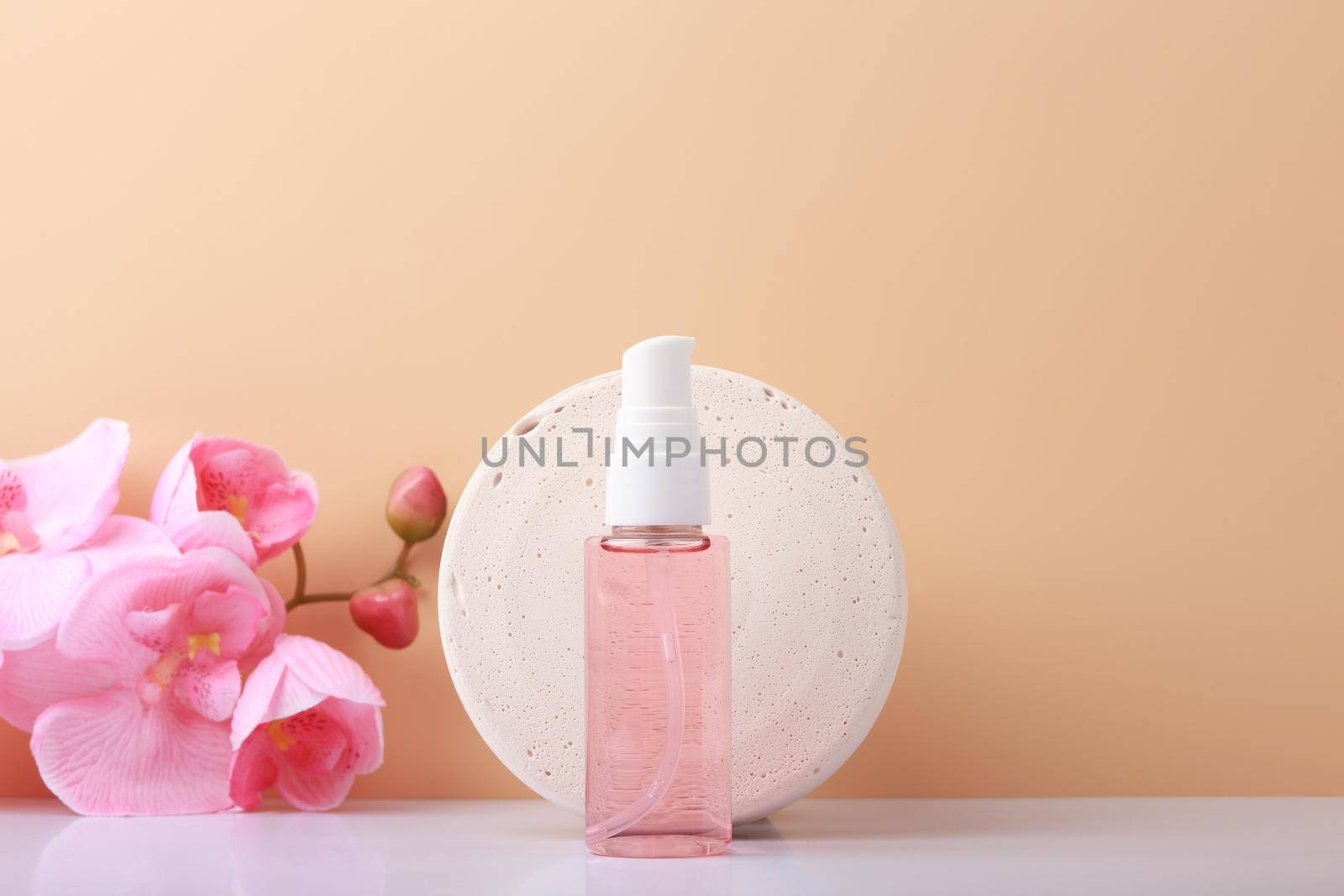 Cleaning foam for skin care against beige background with copy space, round stone podium and pink flower. Concept of natural beauty products for daily skin care and beauty