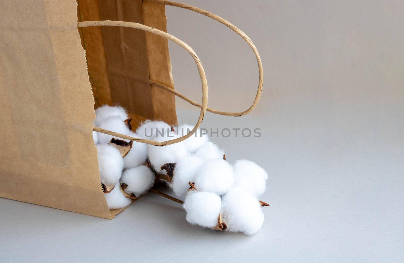 Organic eco-friendly paper bag with cotton flowers on a gray background. Zero waste and eco-friendly concept.