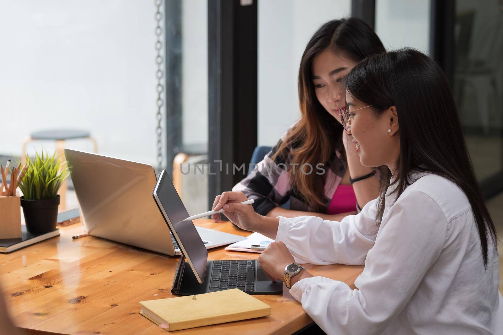 Shot of two young asian female students consulting on their group assignment in library