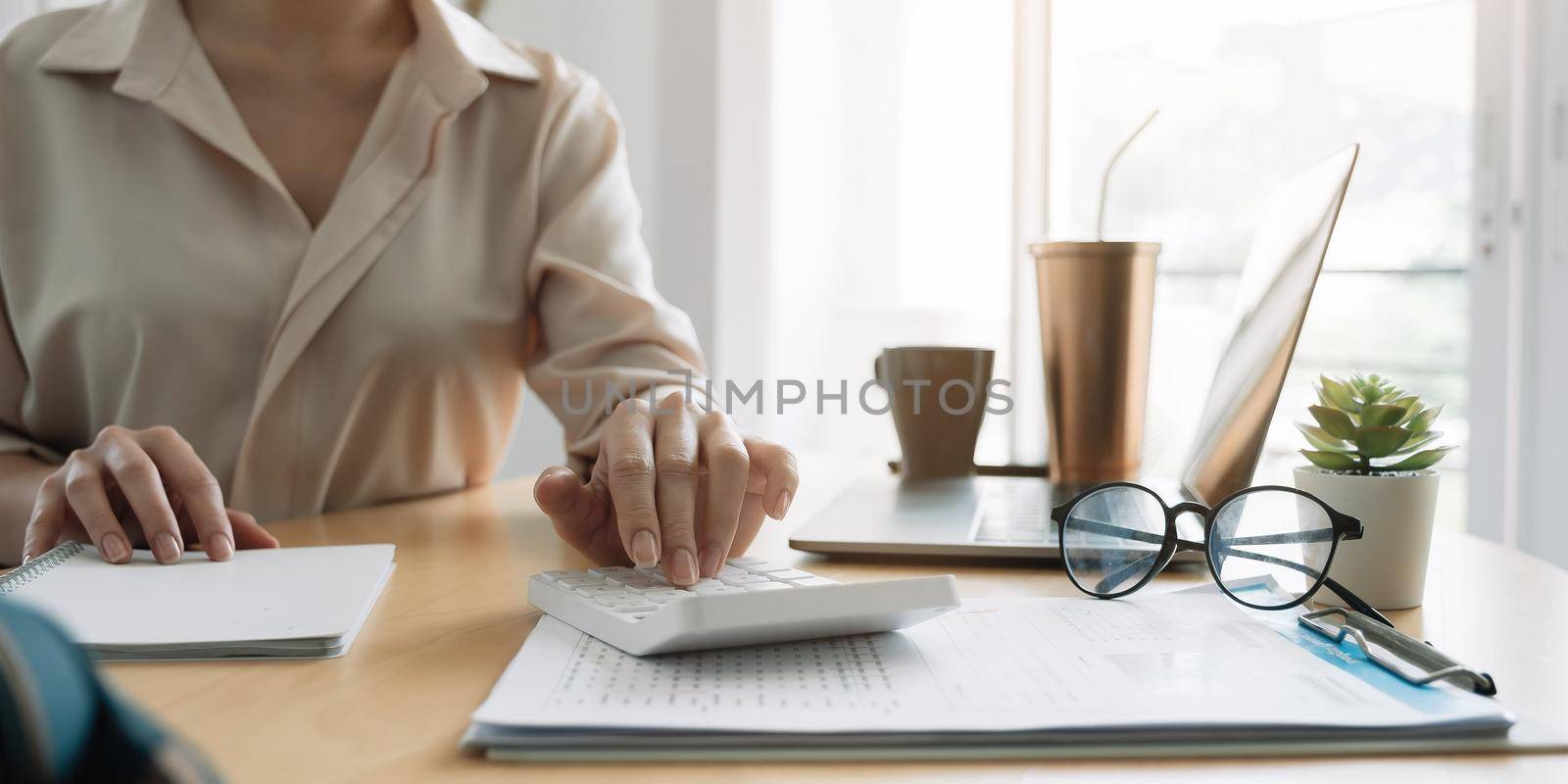 Close up hand of woman using computer calculating household finances or taxes on machine, female manage home family expenditures, using calculator, make payment on laptop by nateemee