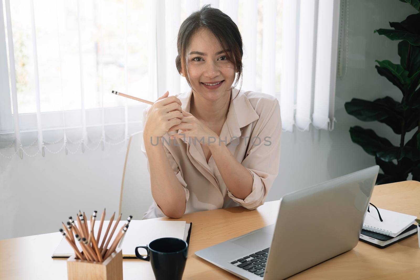 Portrait of young asian woman using laptop at home office by nateemee