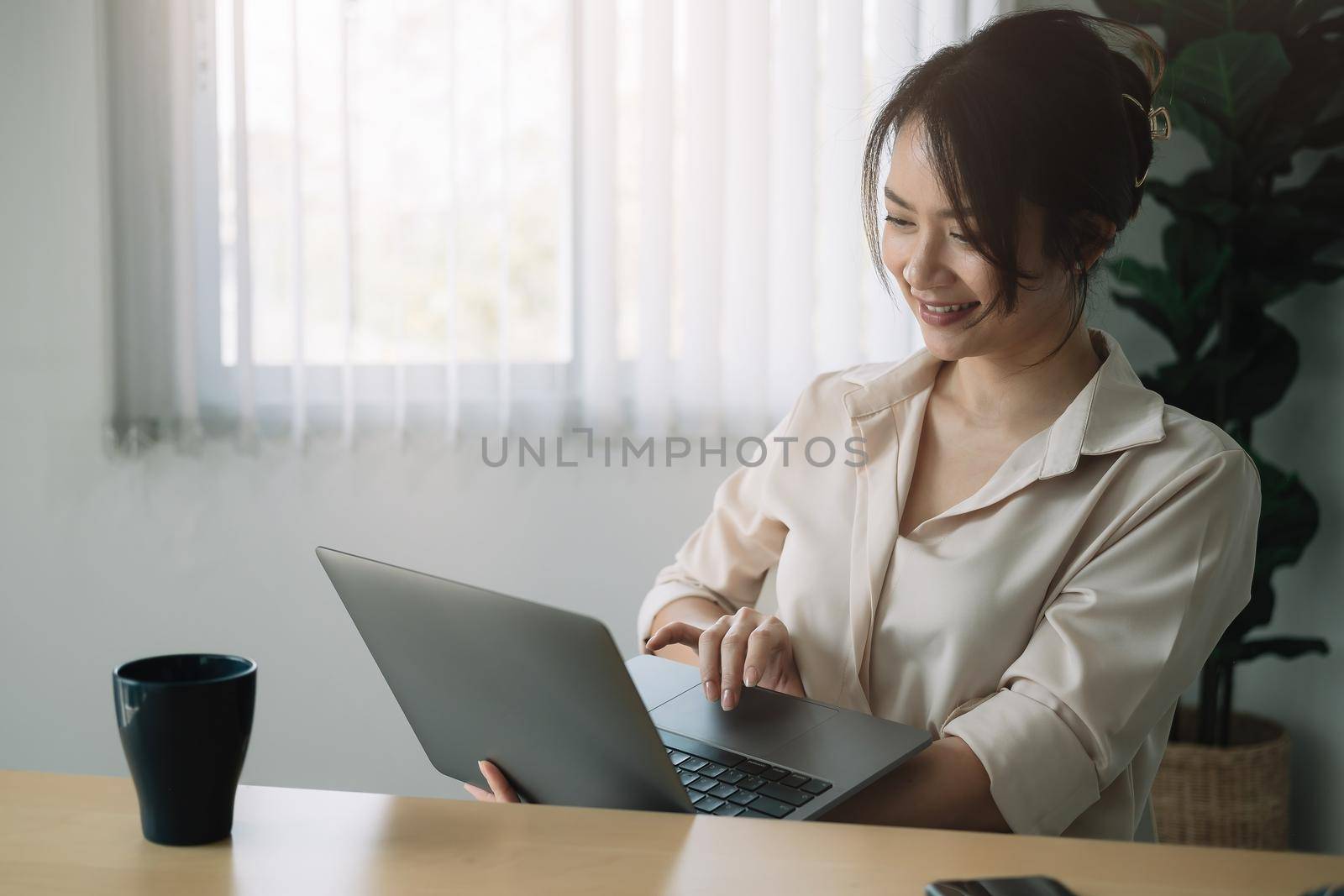 Smiling businesswoman working on laptop at home office - Online conference meeting.