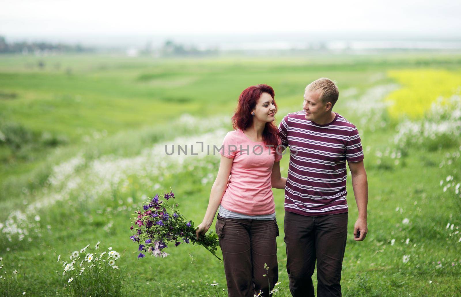 Couple in love guy and girl in a field of white daisies and green grass by selinsmo