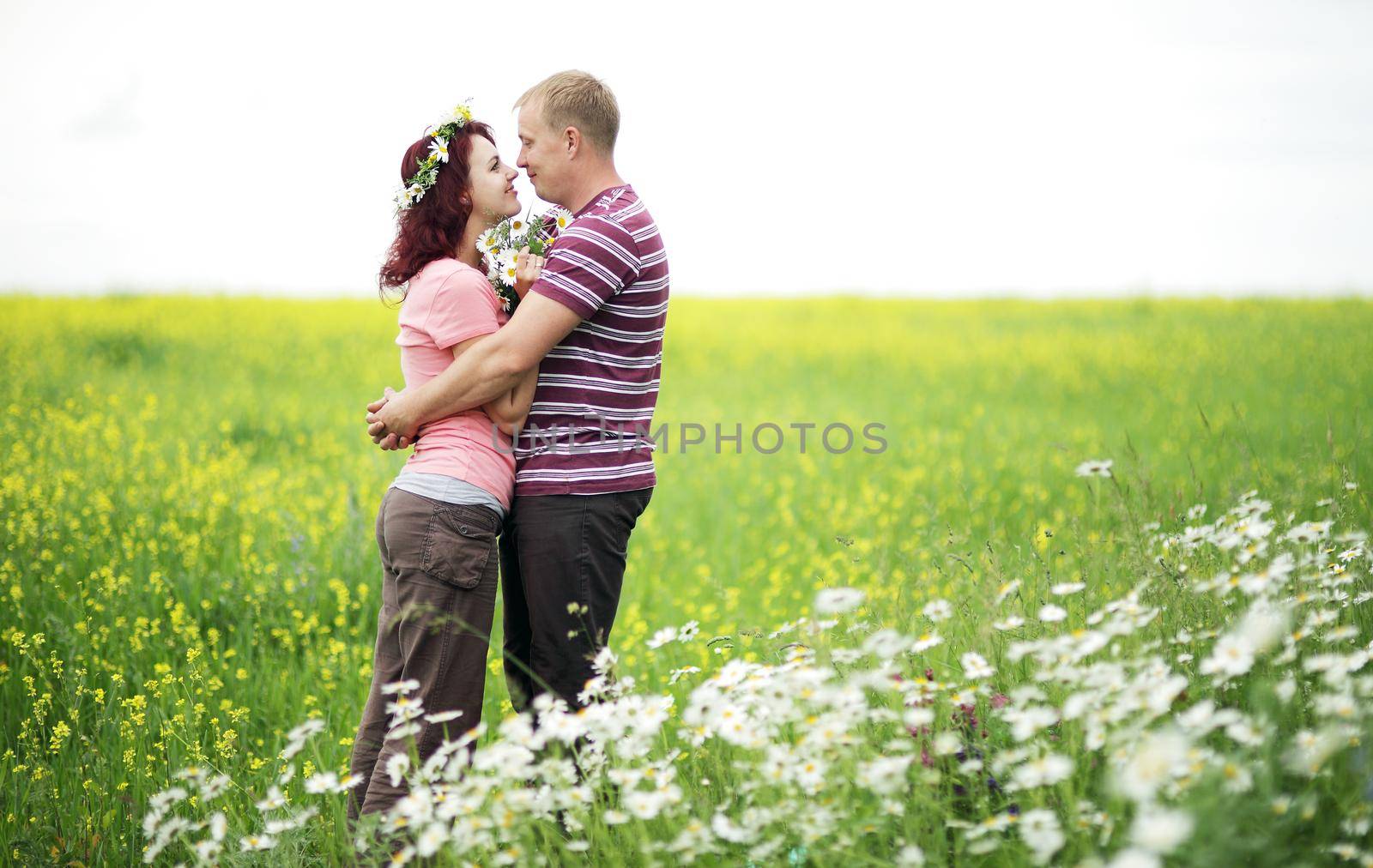 Enamored guy and girl in a green park with white daisies by selinsmo