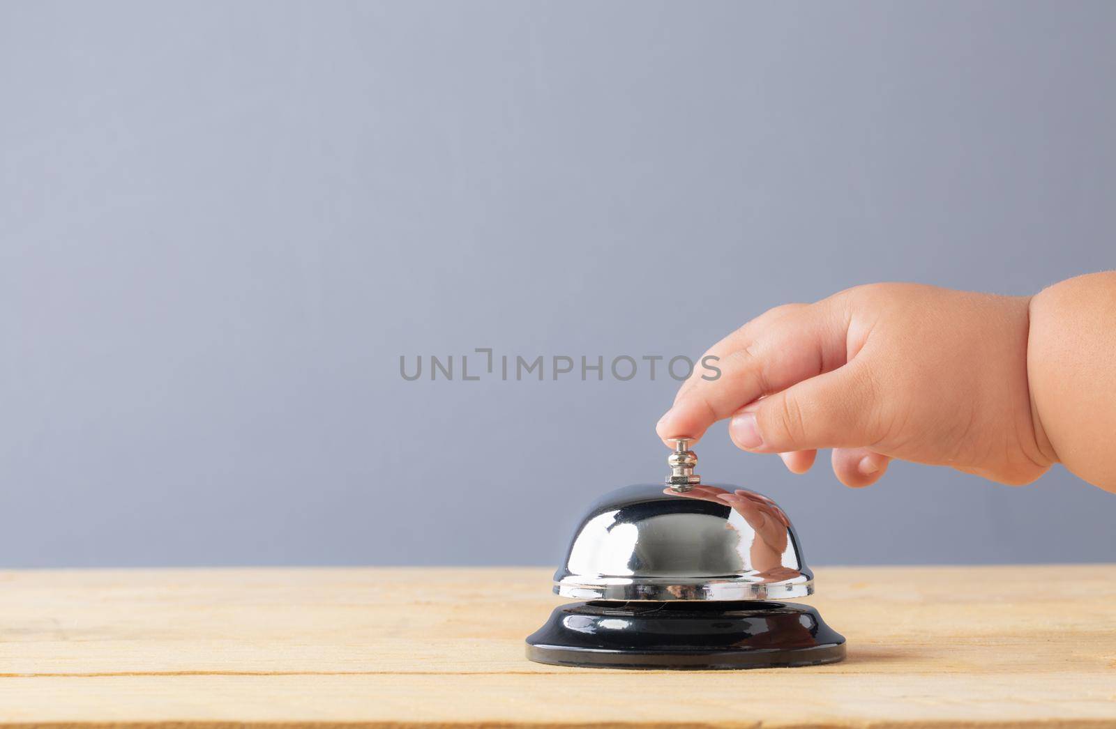 Hand s' child to press the bell service on wood table. Bell of service concept