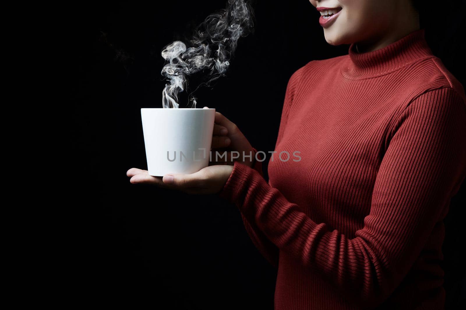 Cup of coffee in the women's hand on dark background