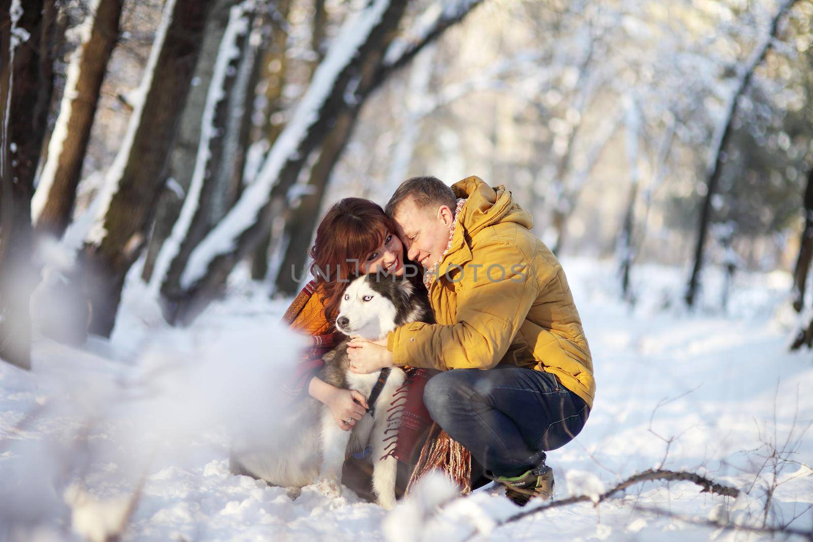 Couple smiling and having fun in winter park with their husky dog by selinsmo