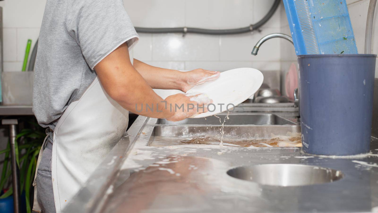 Man washing dish on sink at restaurant