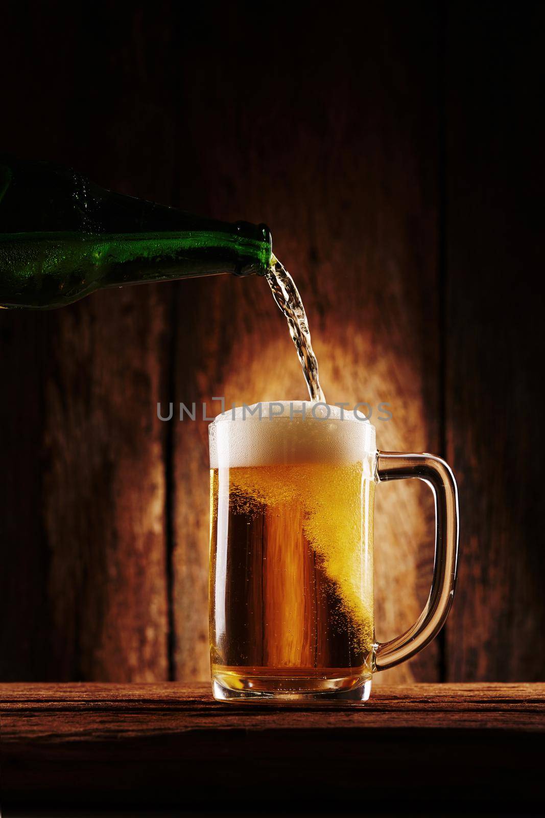 Pouring beer into the glass on wooden background