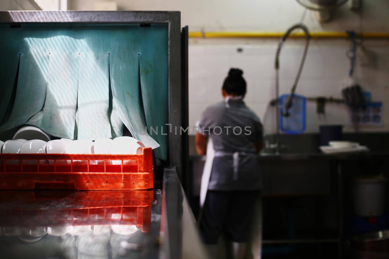 Woman washing dish on sink at restaurant