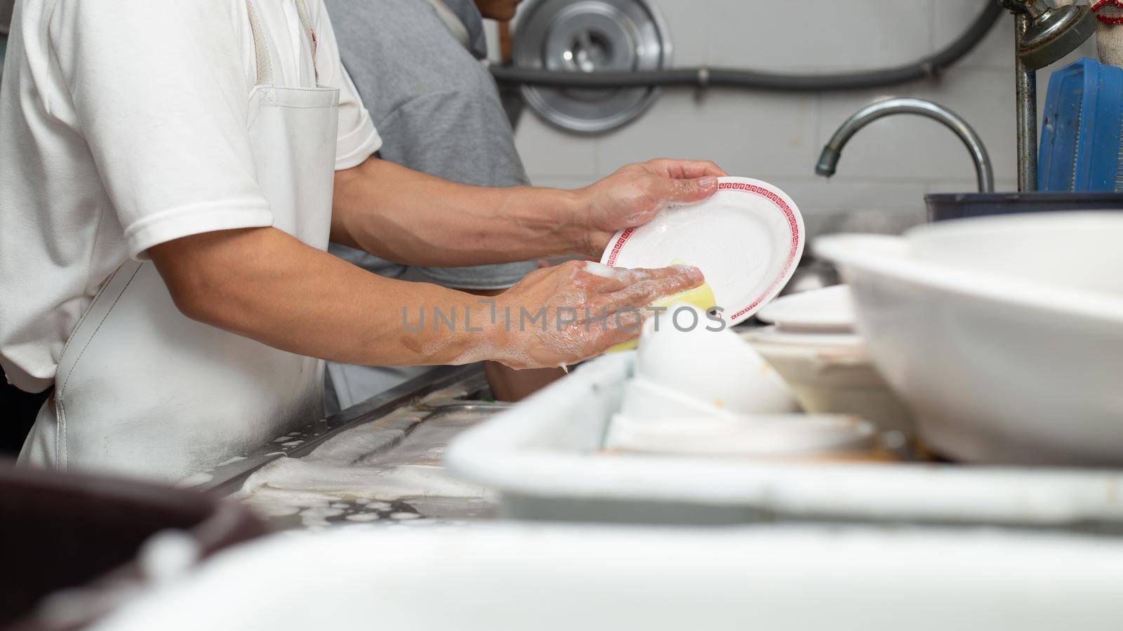 Man washing dish on sink at restaurant