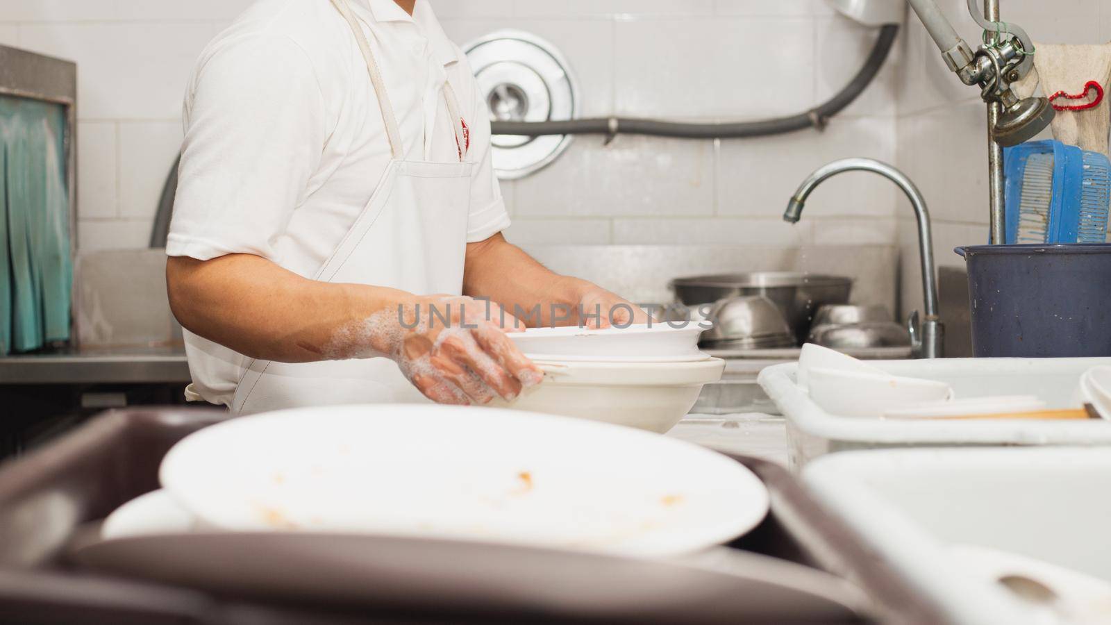 Man washing dish on sink at restaurant