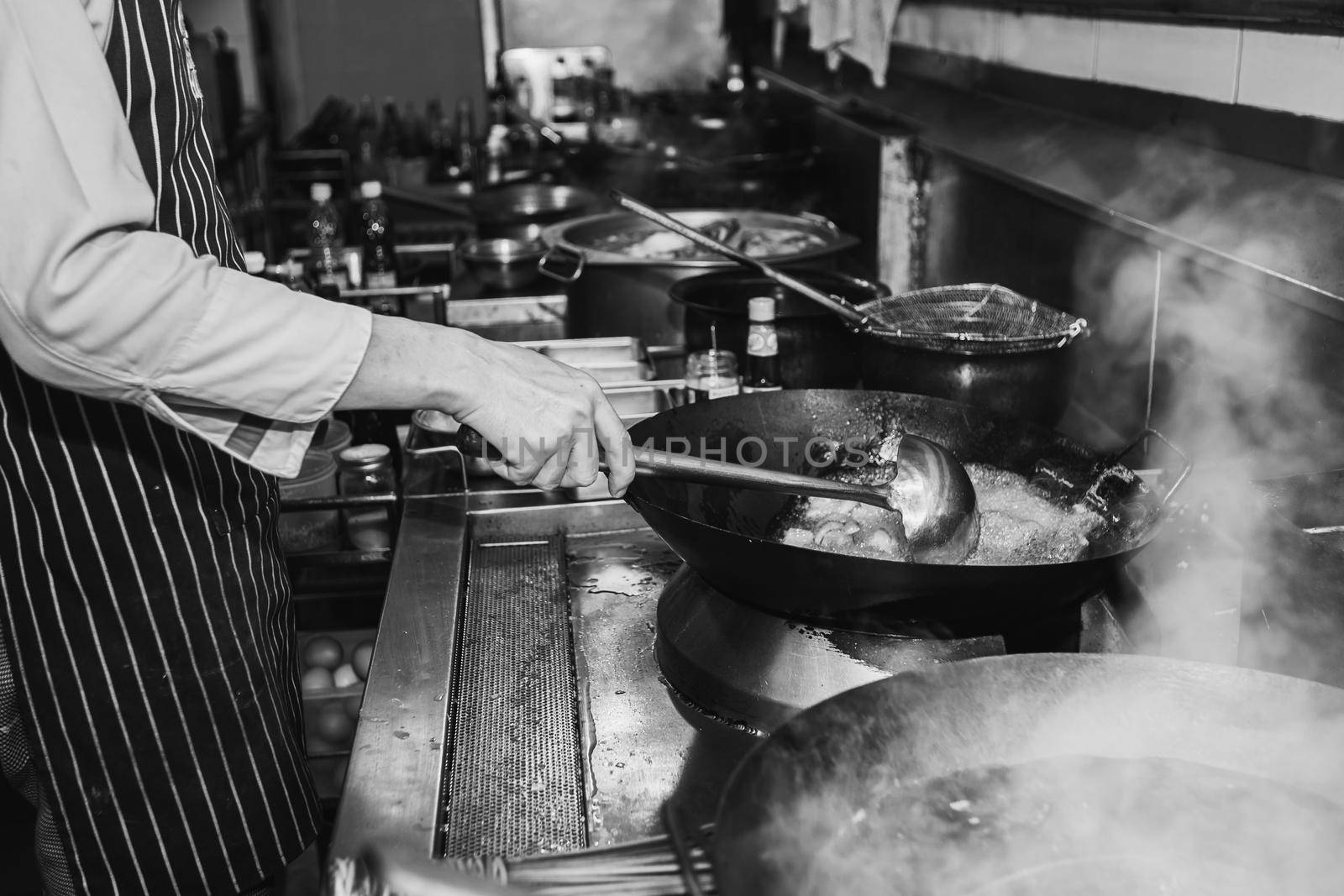 Chef stir fry busy cooking in kitchen. Black and white filter
