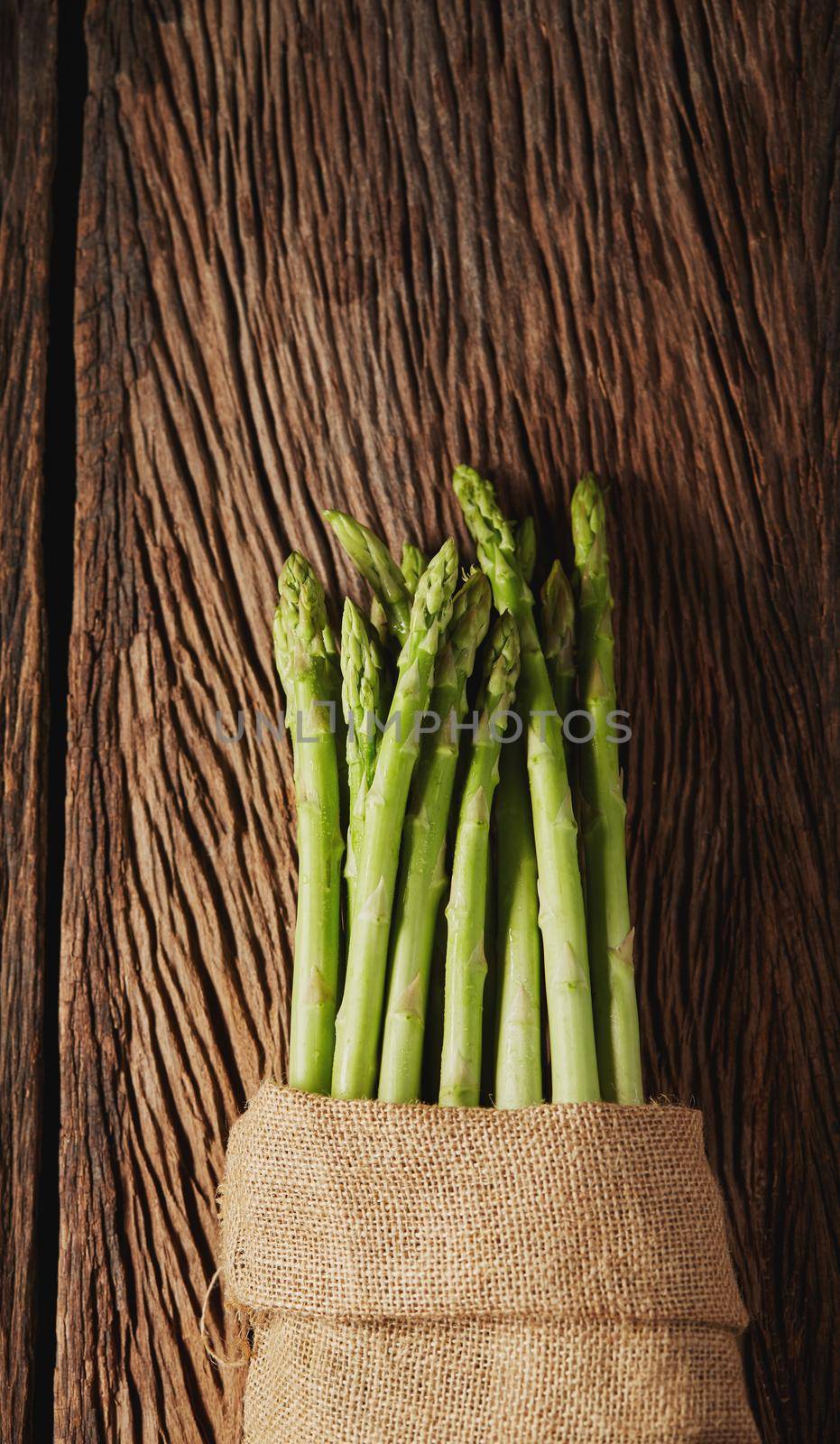 Fresh Asparagus in sack on old wood background