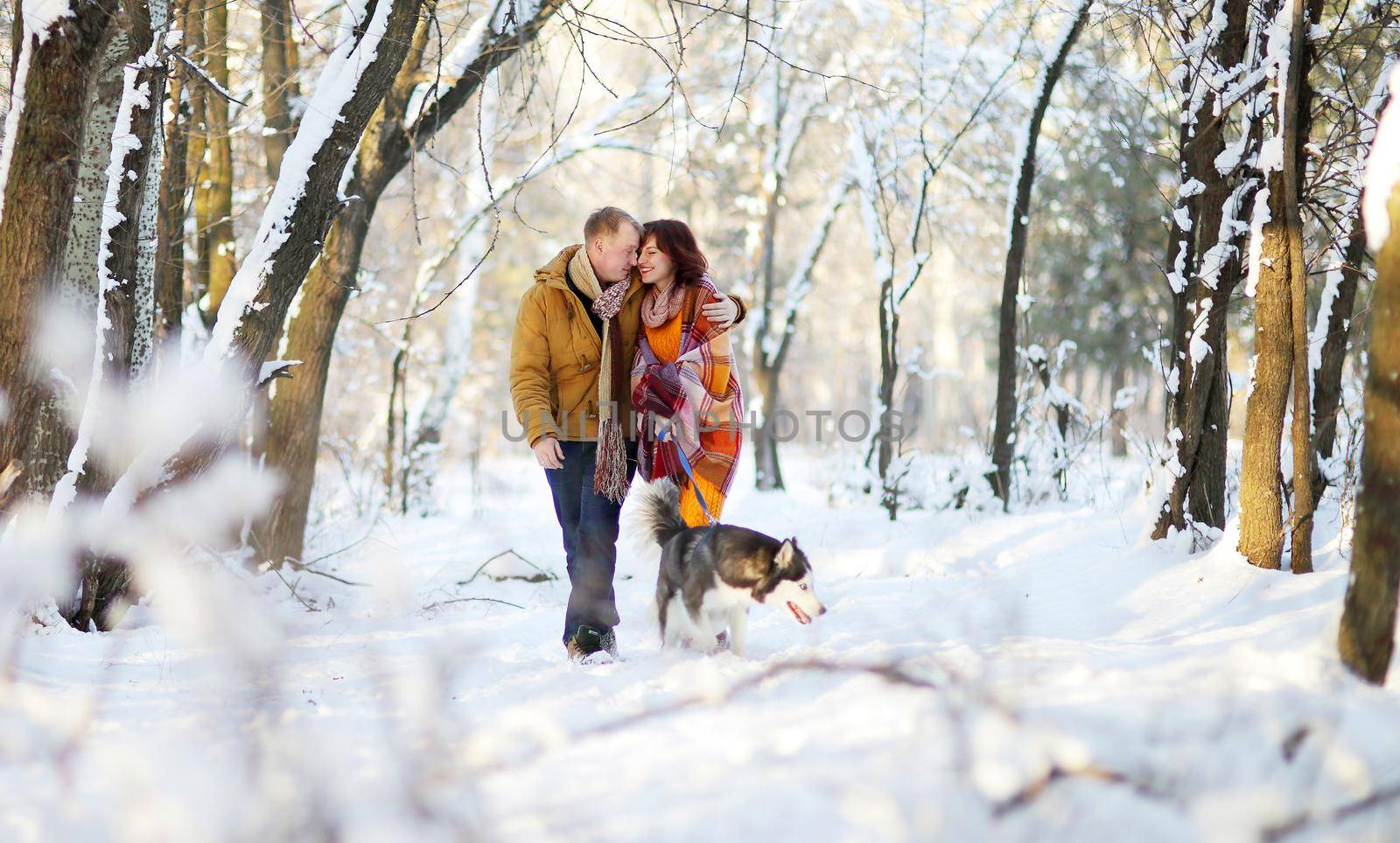Young couple smiling and having fun in winter park with their husky dog by selinsmo