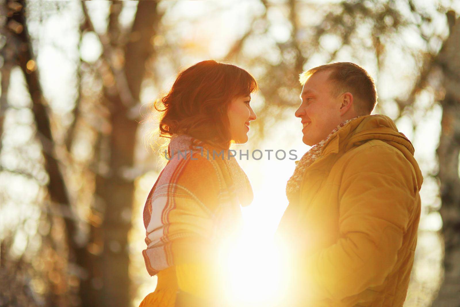 Warm winter portrait of young interracial smiling couple on a walk in the forest by selinsmo
