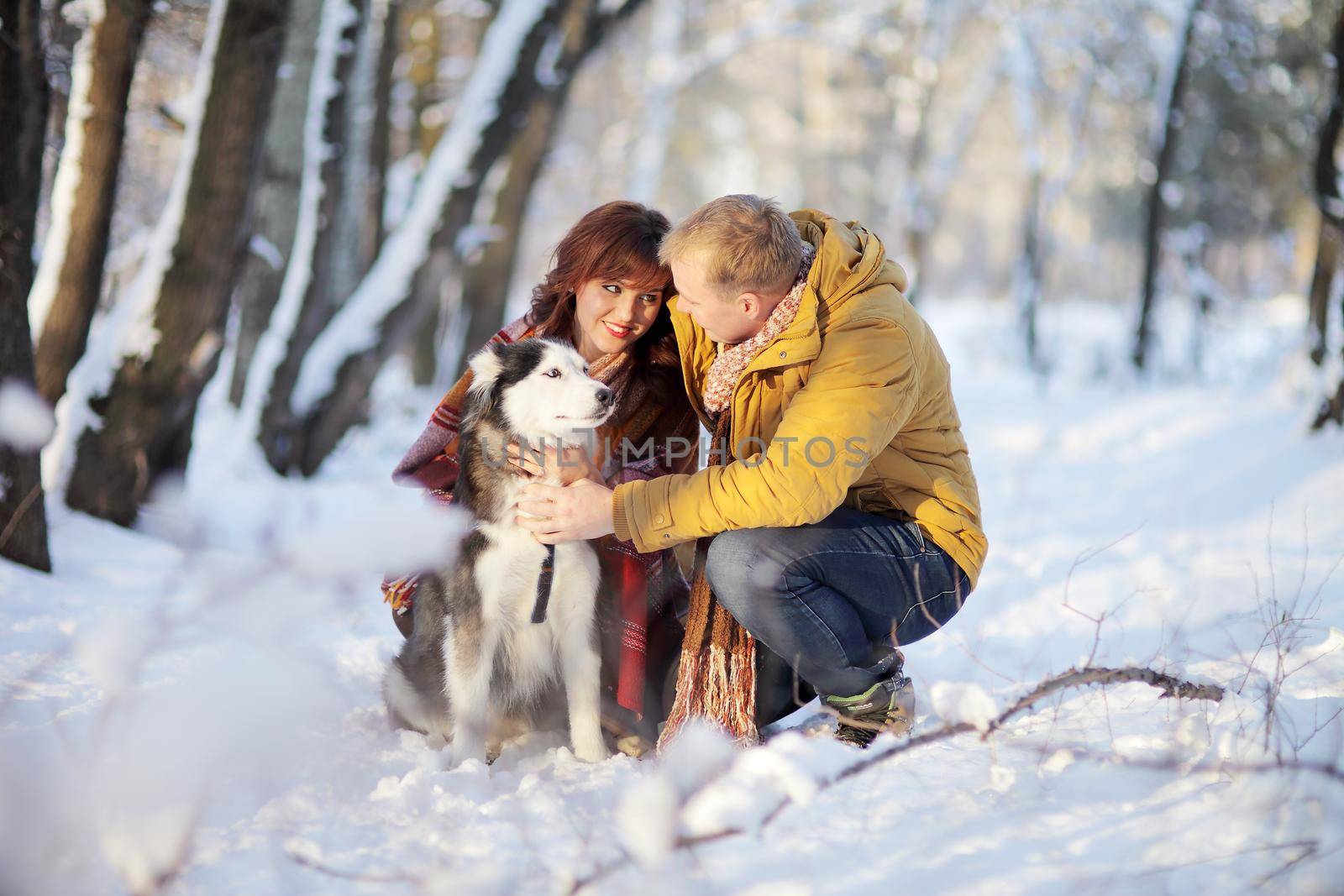 Couple smiling and having fun in winter park with their husky dog by selinsmo