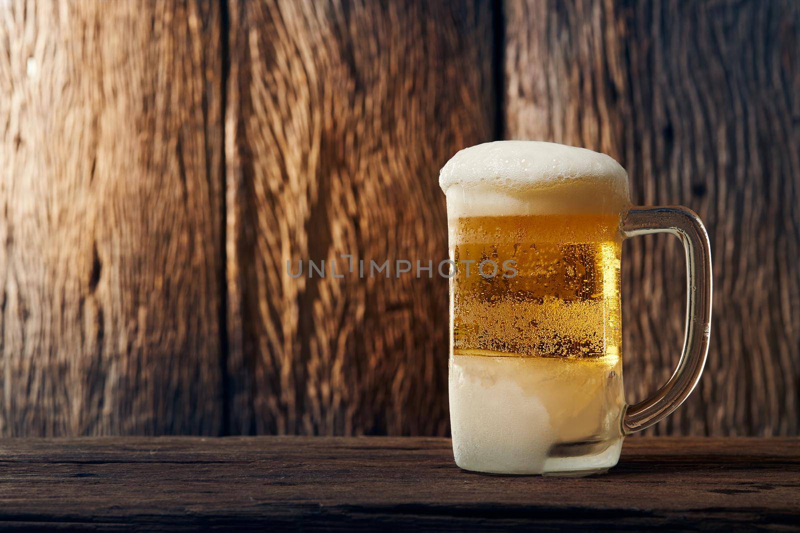 Beer in mug on wooden table with wooden background