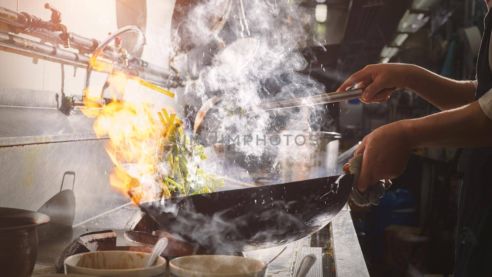 Chef stir fry cooking with wok in restaurant kitchen
