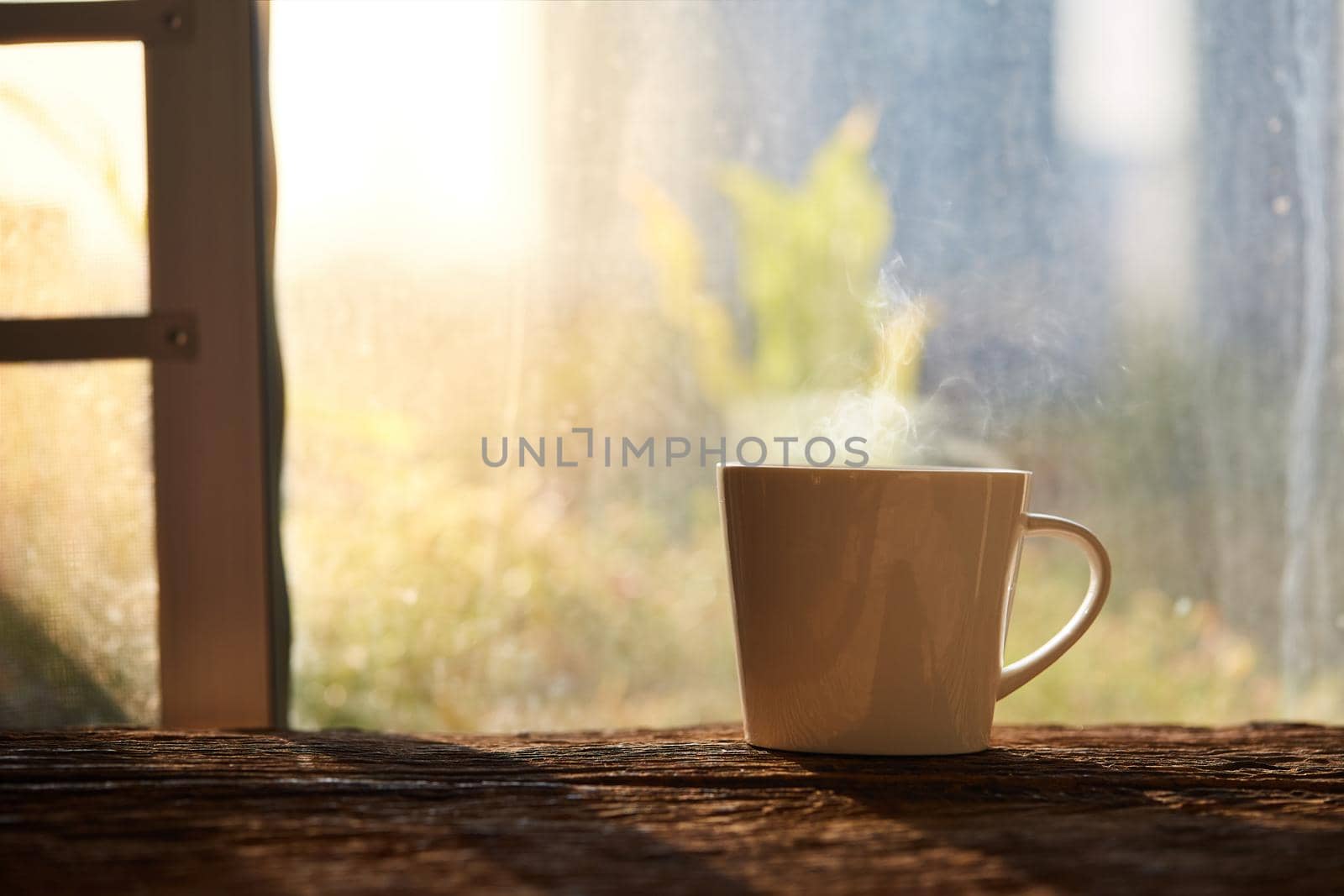 A cup of coffee on the wood floor in the morning sunshine beside window