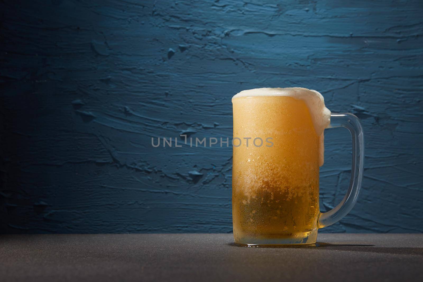 Beer in mug on table with rough blue color background